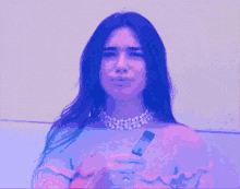 a woman in a pink off the shoulder top is holding something in her hand and making a funny face