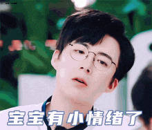 a young man wearing glasses is looking at the camera with chinese writing above him