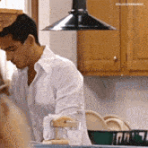 a man in a white shirt is standing in a kitchen with the name colucciyarango on the corner