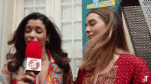 two women standing next to each other with a microphone that says dt