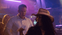 a man in a white shirt and a woman in a cowboy hat are dancing