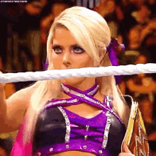 a woman in a purple and black outfit is holding a rope around her neck .