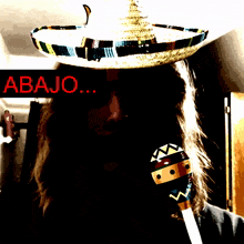 a person wearing a sombrero and holding a maraca with abajo written in red behind them