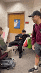 a group of young men are sitting in chairs in a room with a door .