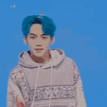 a young man with blue hair is smiling and wearing a purple hoodie .
