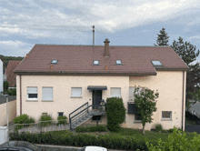 a beige house with a brown roof and stairs leading to the front door
