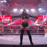 a female wrestler is standing in a ring with her arms outstretched .