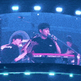 a man singing into a microphone with a nord lead keyboard in the background