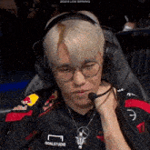 a man wearing headphones and a red bull shirt is sitting in a chair