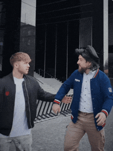 a man in a new york giants jacket stands next to another man in a black jacket