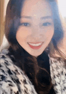 a woman is smiling for the camera and wearing a black and white coat .