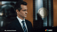 a man in a suit and tie stands in front of a sign that says law and order