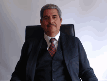 a man wearing a suit and tie is sitting in a chair