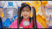 a girl with pigtails is smiling in front of a group of girls in costumes