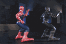 two spiderman action figures are dancing together in a dark room
