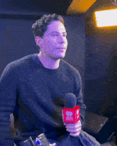 a man in a black sweater is holding a red microphone that says iheart radio