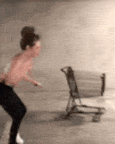 a woman without a shirt is running towards a shopping cart .