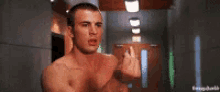 a shirtless man is standing in a hallway making a funny face .