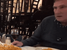 a man sitting at a table with a glass of wine and a plate of food
