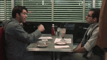 two men are sitting at a diner table with a bottle of ketchup on the table