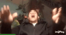 a man in a black jacket is screaming with his hands in the air