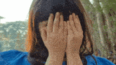 a woman covering her face with her hands in a blue dress
