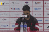 a man sits at a table with a can of coca-cola and a bottle of water