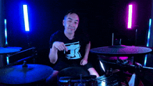 a man sitting in front of a drum set making a heart sign