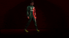 a man in a green aston martin jumpsuit is standing in front of a red background