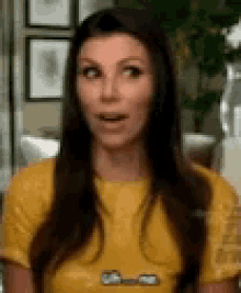 a woman in a yellow shirt is making a surprised face while talking to someone .