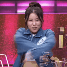 a woman in a blue jacket with a name tag on her chest is dancing on a stage .