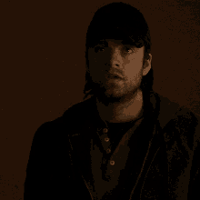 a man with a beard is wearing a baseball cap and a hoodie .