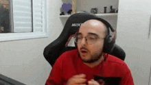 a bald man wearing headphones and glasses is sitting in front of a computer .
