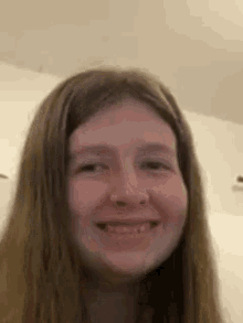 a young girl with long brown hair is smiling and looking at the camera .