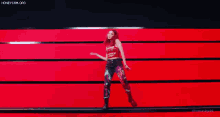 a woman with red hair is dancing on a stage in front of a red wall .