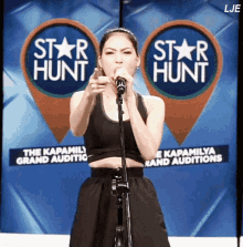 a woman is singing into a microphone in front of a sign that says star hunt