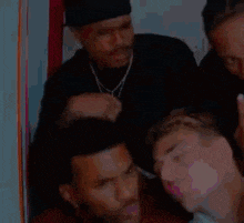 a group of men are standing around a man laying on a bed .