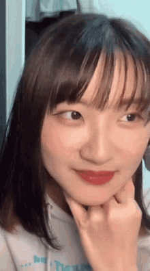 a close up of a girl 's face with her hand on her chin .