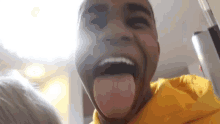 a man wearing a yellow hoodie sticking his tongue out