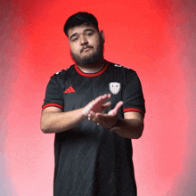 a man with a beard wearing a black adidas shirt