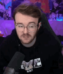 a man wearing glasses is sitting in front of a microphone and talking into it .