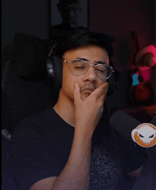 a man wearing glasses and headphones with a skull sticker on his shirt