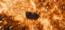 a black object is flying through the air in front of a large fire