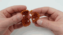 a person is holding two balls in their hands that look like earrings