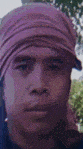 a close up of a man wearing a purple head scarf