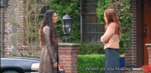 two women standing in front of a brick building with the words where are you heading on the bottom