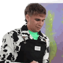 a man is wearing a cow print jacket and overalls .