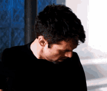 a close up of a man wearing a black shirt and looking down .