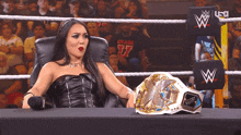 a woman sitting in a chair next to a wrestling belt that says x