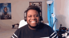 a man wearing headphones and a microphone smiles in front of a poster that says go ninja